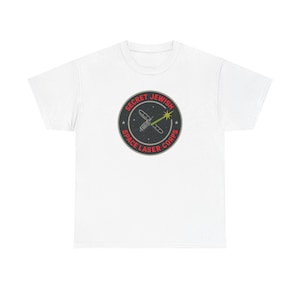 May include: White t-shirt featuring a circular graphic with the text "SECRET JEWISH SPACE LASER CORPS". The graphic includes a spaceship, a laser beam, and stars, all in a black, red, and green color scheme.
