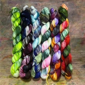 May include: Seven skeins of colourful yarn, each with a unique pattern of swirls and speckles. The yarn colours include green, purple, blue, pink, orange, and brown.