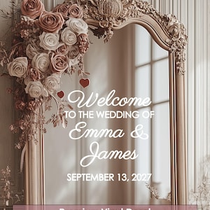 May include: A decorative gold-framed mirror with floral accents and the text "Welcome to the Wedding of Emma & James, September 13, 2027." The mirror is adorned with roses in shades of pink and white, creating an elegant wedding decoration.