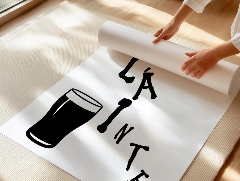May include: A white poster with a black graphic of a pint glass and the words "LA PINTE" in black. The poster is being unrolled by a person. The poster is on a light-colored rug.