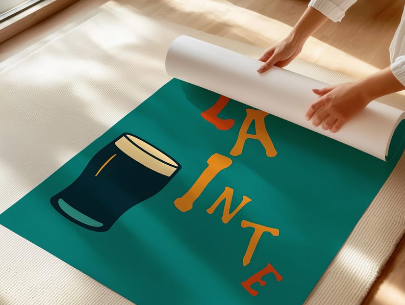 May include: A teal-colored yoga mat with a graphic of a pint of beer and the words "LA PINTE" in orange. The mat is being unrolled by a person. The beer glass is dark blue with a tan rim.