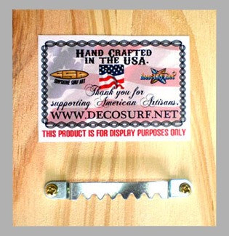 May include: A wooden plaque with a printed label and a metal sawtooth hanger. The label reads "HAND CRAFTED IN THE USA" and "Thank you for supporting American Artisans." The website address is www.DECOSURF.NET. The text "THIS PRODUCT IS FOR DISPLAY PURPOSES ONLY" is also visible.