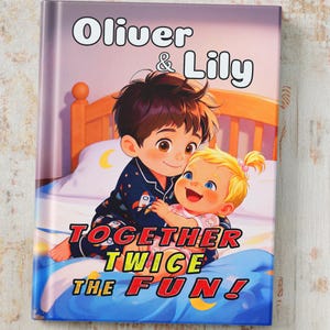 Peut inclure: Un livre relié intitulé Oliver & Lily Together Twice The Fun! illustré d'un enfant aux cheveux bruns en pyjama à motifs de fusées serrant un bébé blond dans ses bras sur un lit avec une tête de lit en bois et une couverture bleue.