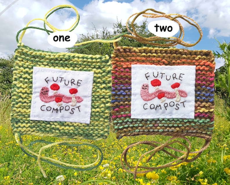 以下が含まれることがあります： 「Future Compost」という文字と、刺繍されたミミズとキノコが描かれた、2つのニット製の壁掛け。壁掛けは緑と茶色で、黄色とオレンジのストライプが入っています。