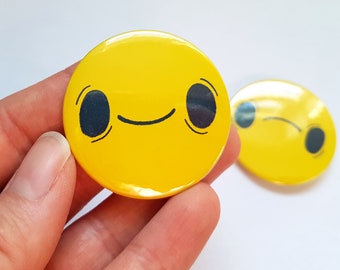 Botón de pin con insignia amarilla de 45 mm con cara sonriente y ceño fruncido