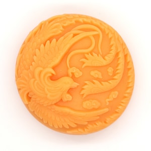 May include: A round, orange soap bar with a detailed carving of a phoenix bird. The soap has a traditional Chinese design.