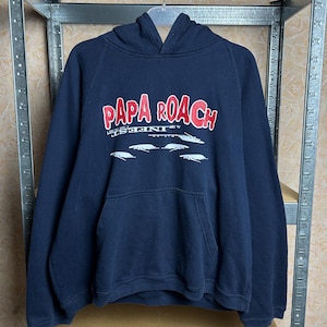 Può includere: Felpa con cappuccio blu navy con il nome della band "PAPA ROACH" in lettere rosse e bianche. Sotto il nome della band ci sono grafiche di insetti bianchi. Ha una tasca frontale e un cappuccio con coulisse.