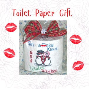May include: A roll of white toilet paper wrapped in clear plastic, topped with a red and green plaid bow and a small white snowflake. The paper features embroidered snowmen kissing with the text Snowflake Kisses and Winter Wishes.
