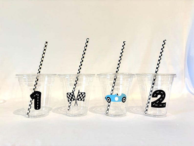 Puede incluir: Cuatro vasos de pl&aacute;stico transparente con pajitas a cuadros blancos y negros. Cada vaso tiene un tema de carreras: el n&uacute;mero 1, banderas a cuadros, un coche de carreras azul y el n&uacute;mero 2. Ideal para una fiesta tem&aacute;tica de coches de carreras.