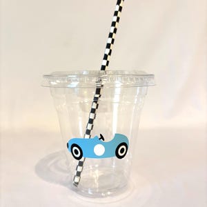 Puede incluir: Un vaso de pl&aacute;stico transparente con tapa y pajita a cuadros blancos y negros. El vaso tiene un gr&aacute;fico de coche de carreras azul claro. Para bebidas fr&iacute;as.