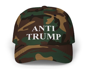 May include: A camouflage baseball cap with the text "ANTI TRUMP" in white lettering.