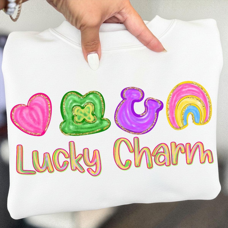 May include: White sweatshirt with a colorful "Lucky Charm" design. The design includes a pink heart, green shamrock, purple ampersand, and a rainbow. The text "Lucky Charm" is in a gradient font.