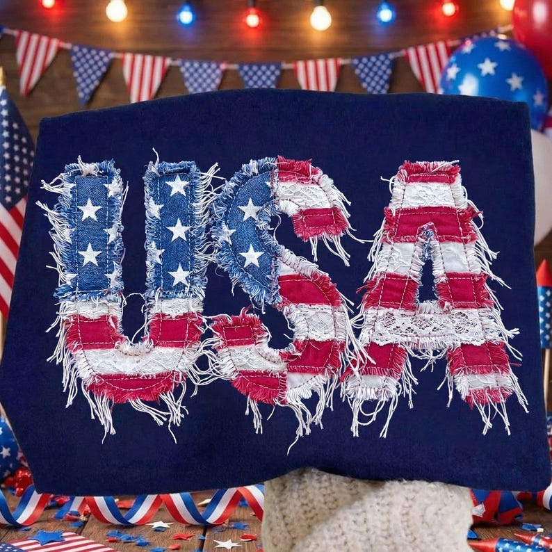 May include: A navy blue textile with the word "USA" appliqu&eacute;d in red, white, and blue fabric. The letters have a distressed, frayed edge, and the "U" and "S" feature white stars.