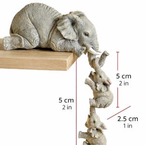 May include: A gray elephant figurine with three smaller elephants hanging below. The largest elephant is 10 cm (3.9 in) long, and the smaller elephants are 2.5 cm (1 in) wide and 5 cm (2 in) tall. The figurine is on a wooden shelf.