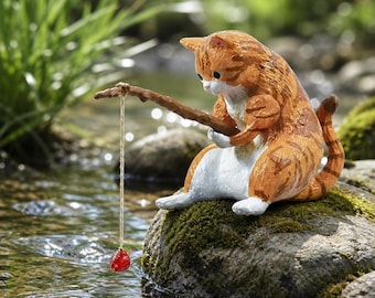 May include: A whimsical figurine of a ginger tabby cat fishing with a twig and string. The cat is seated on a mossy rock in a stream, holding the twig with a red, round lure dangling in the water. The cat has white paws and belly.