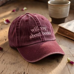 May include: A maroon baseball cap with the text "will yap about books" embroidered in white.