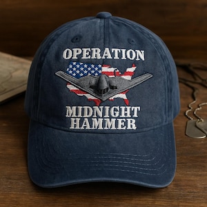 May include: Navy blue baseball cap featuring the text "OPERATION MIDNIGHT HAMMER" above and below a graphic of a stealth bomber over a map of the United States, with the American flag incorporated into the design.