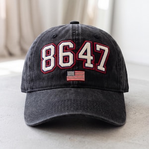 May include: A black baseball cap with the number "8647" in white with red trim and a small American flag patch. The cap is made of a worn, faded fabric.