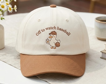 Gorra de béisbol con pato bordado y el gráfico "Off to Watch Baseball" (De camino a ver béisbol).