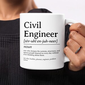 May include: White ceramic mug with the text "Civil Engineer" and a definition. The definition describes the role of a civil engineer. The mug is held by a person.