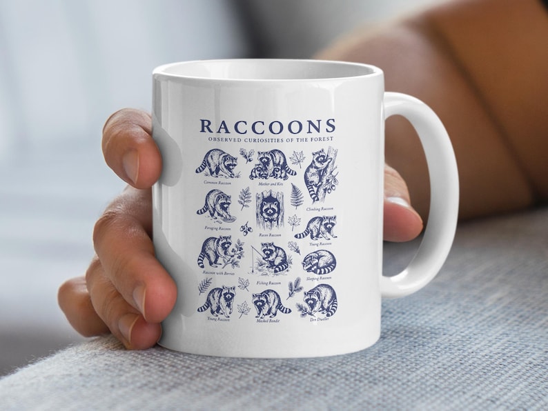 White mug with blue illustrations and text about raccoons and their behaviors.