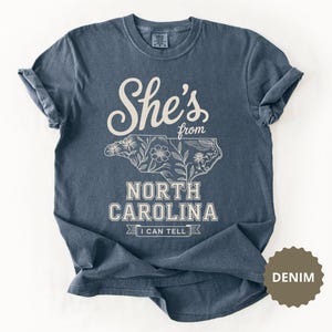 Navy t-shirt with "She's from North Carolina" and floral state outline.