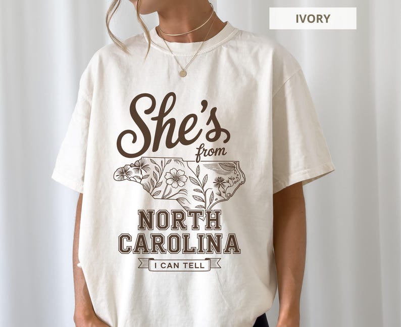 T-shirt with "She's from North Carolina, I can tell" text and floral outline of NC.