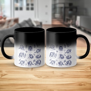 Two black ceramic mugs with navy blue illustrations of raccoons in various poses.