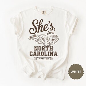 White t-shirt with "She's from North Carolina I Can Tell" and floral map.