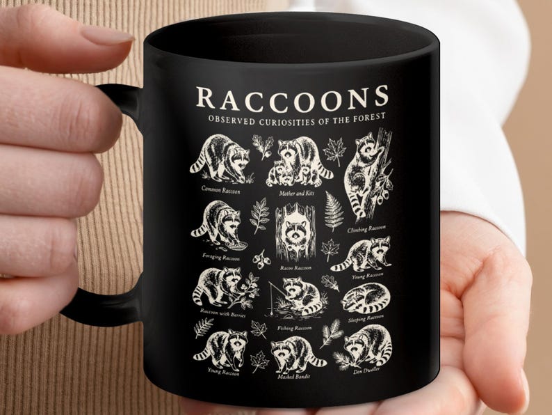Black mug with cream-colored raccoon illustrations and labels, each showing different raccoon activities.