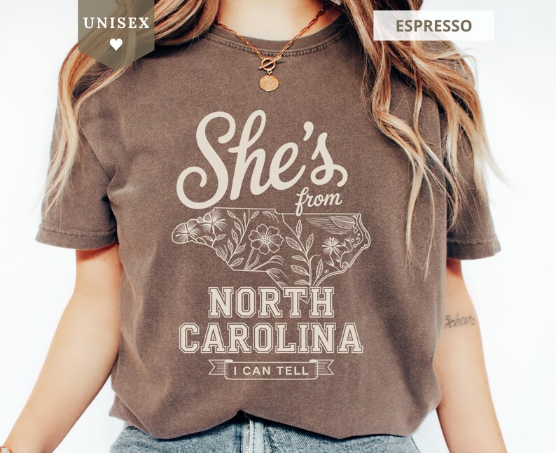 Brown unisex t-shirt with "She's from North Carolina" and floral design.