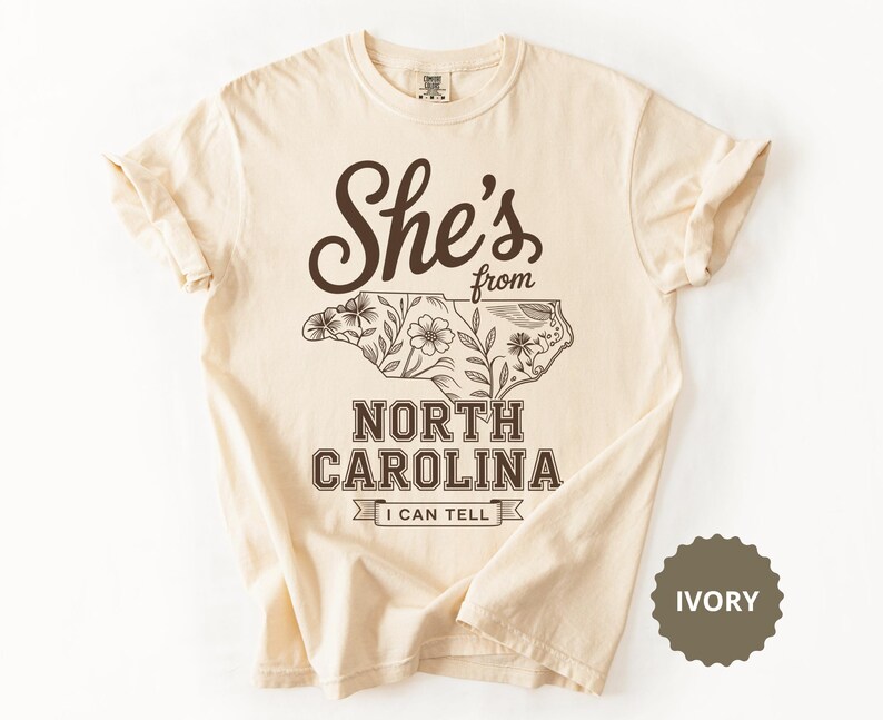 Cream t-shirt with "She's from North Carolina I Can Tell" text and floral outline.