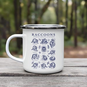 White enamel mug with illustrations and text about raccoons in various poses.