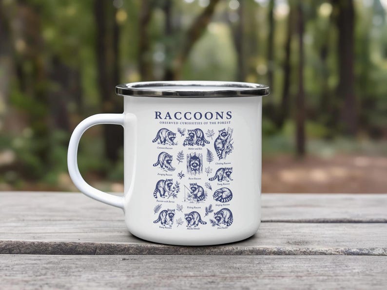 White enamel mug with illustrations and text about raccoons in various poses.