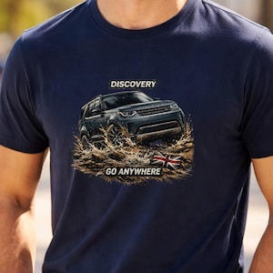 May include: Dark blue t-shirt featuring a vehicle graphic with the words "DISCOVERY" and "GO ANYWHERE". A British flag is also shown. The person is wearing sunglasses and is standing outside.