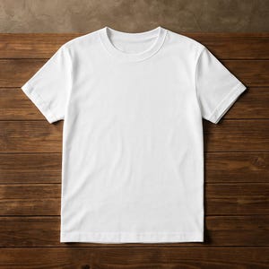 Pode incluir: Uma camiseta branca lisa de manga curta. A camiseta tem gola redonda e é feita de um tecido macio e opaco. A camiseta é exibida em uma superfície de madeira.
