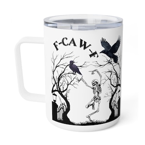 Puede incluir: Taza de viaje blanca con una ilustración en blanco y negro de un esqueleto bailando en un bosque espeluznante con cuervos. El texto "F-CAW-F" está encima de la escena. La taza tiene un asa blanca y una tapa transparente.