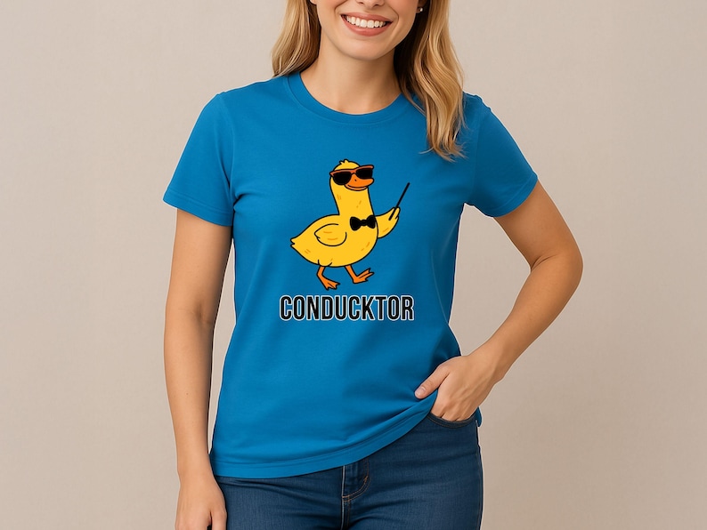 T-shirt featuring a cartoon duck wearing sunglasses and a bow tie, holding a conductor’s baton, with the word “CONDUCKTOR” printed below as a music pun.