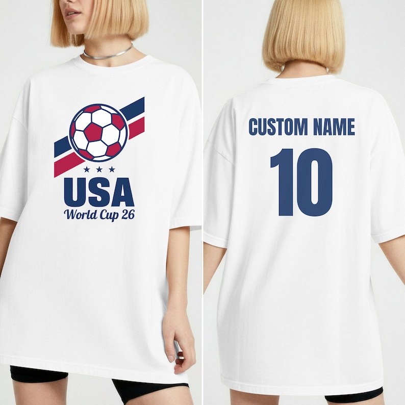 Puede incluir: Camiseta blanca con un gr&aacute;fico de bal&oacute;n de f&uacute;tbol, texto "USA World Cup 26" y el n&uacute;mero 10. La parte trasera de la camiseta tiene "CUSTOM NAME" en azul. La camiseta tiene un corte holgado y oversize.