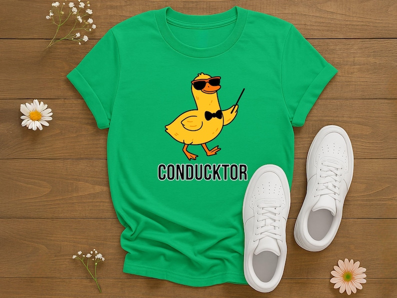 T-shirt featuring a cartoon duck wearing sunglasses and a bow tie, holding a conductor’s baton, with the word “CONDUCKTOR” printed below as a music pun.