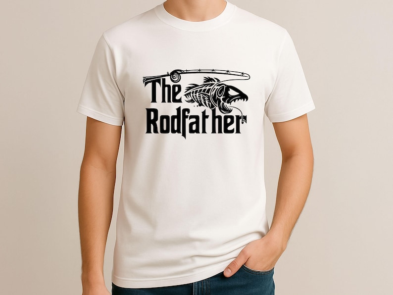 Puede incluir: Camiseta blanca con un gr&aacute;fico negro. El gr&aacute;fico presenta una ca&ntilde;a de pescar, un esqueleto de pez y las palabras "The Rodfather". La camiseta es de manga corta y tiene cuello redondo.
