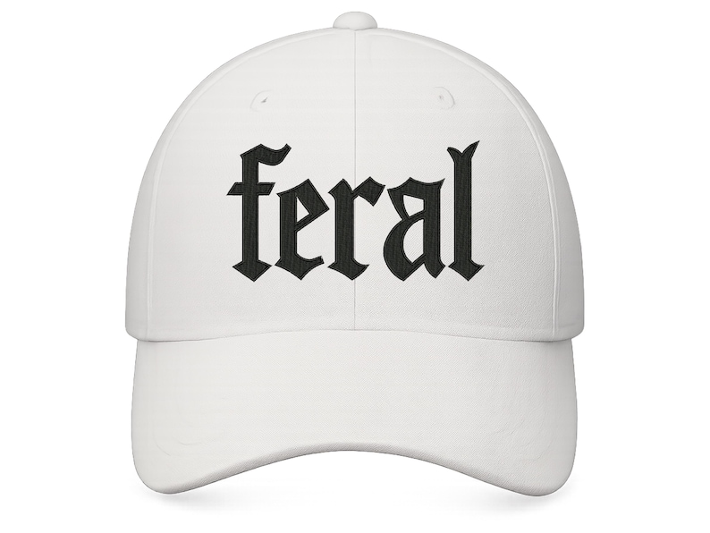Op de afbeelding: Witte baseballcap met het woord "feral" geborduurd in zwarte gotische letters. De cap heeft een gebogen klep en een knoop aan de bovenkant. Een casual accessoire.
