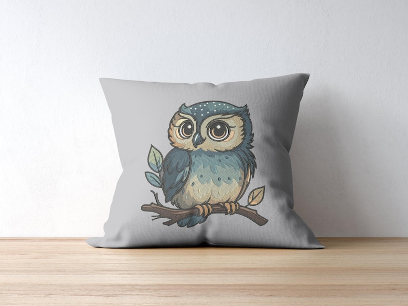 May include: A decorative gray pillow featuring a watercolor illustration of a cartoon owl perched on a branch. The owl has large eyes, blue and tan feathers, and is surrounded by green leaves. The pillow is on a wooden surface.