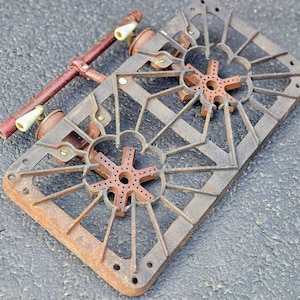 May include: A vintage cast iron stove top with two burner grates. The grates are rusty and have a starburst design. The stove top is missing the burners.