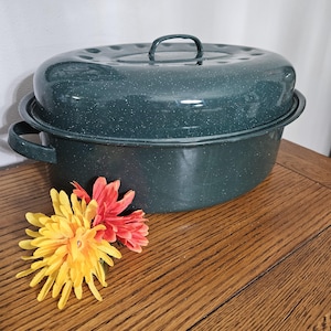 May include: A dark green enamel roasting pan with a lid. The pan has a speckled finish and a handle on the lid.