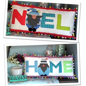 Op de afbeelding: Twee decoratieve kussens met een gnome-ontwerp. Het eerste kussen is rood, blauw en groen met het woord "NOEL" erop. Het tweede kussen is roze, blauw en groen met het woord "HOME" erop. Beide kussens zijn 14 inch bij 28 inch.