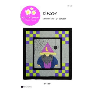 May include: A Halloween-themed quilt featuring a gnome wearing a purple wizard hat with a crescent moon and stars. The quilt has a gray background with a spiderweb and a black border. The quilt measures 29 inches by 31 inches.
