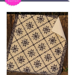 May include: A quilt pattern called "Frosting" by Charisma Horton. The quilt is made with a white fabric with a black and white star pattern. The quilt is 80 inches by 92 inches.