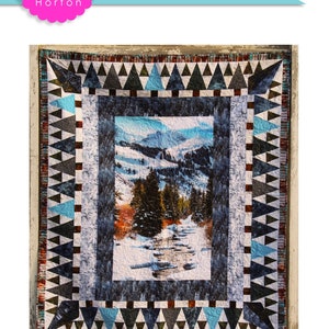 May include: A quilt pattern featuring a winter scene with a river, trees, and mountains. The quilt is framed with a geometric border of black, white, blue, and brown triangles. The quilt is 60 inches by 70 inches. The title of the pattern is "Stay 'Till Winter".