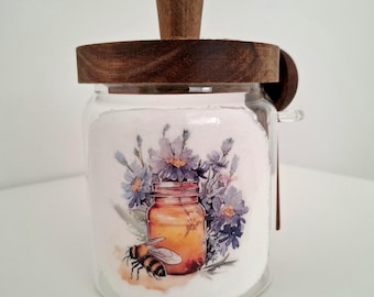 Tarro de miel de cristal con tapa de madera y cuchara.
